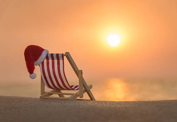 Deckchair with christmas santa hat at ocean beach during sunset