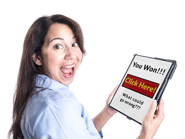 Young Woman Reacts Happily to Winning Prize on her Tablet. A young woman is overjoyed by message on her tablet computer stating she has won a prize, not realizing it is a scam. phishing photos stock pictures, royalty-free photos & images