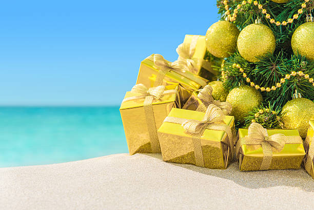 istock Christmas tree with golden decorations and gifts at beach 498462712