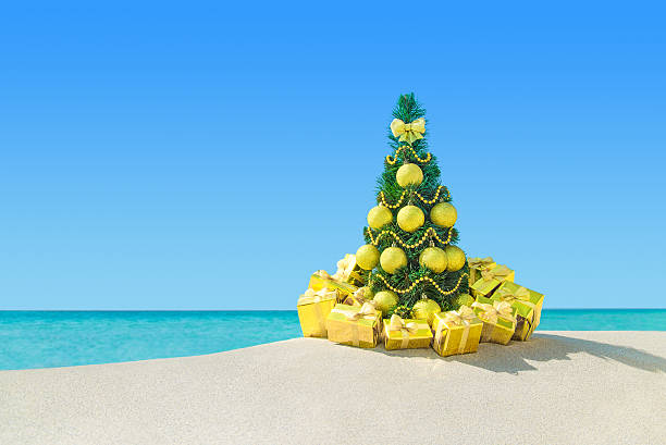 istock Christmas tree with golden decorations and gift boxes at beach 498463424