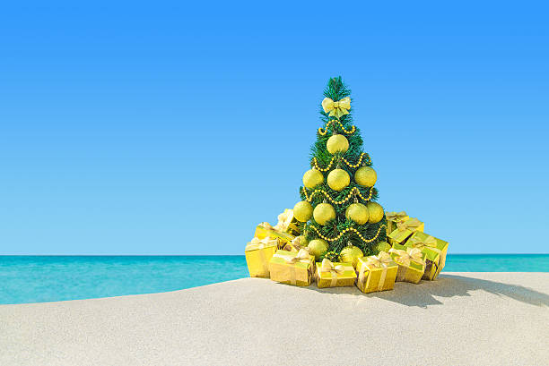 árvore de natal com caixas de presente de ouro e decorações na praia - christmas tree bead humor imagens e fotografias de stock