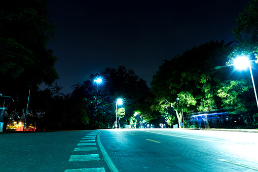 Quiet suburban street at night - illuminated by glowing streetlights - houses lined up - parked cars - clear, starless sky. Taken in Toronto, Canada.