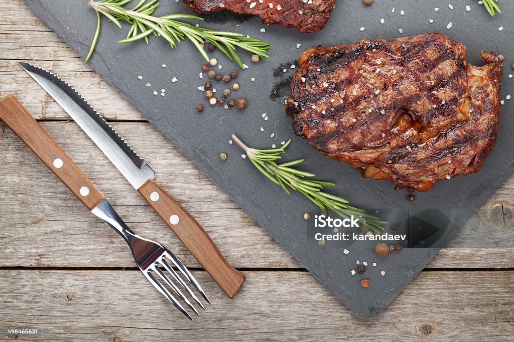 Beef steaks with rosemary and spices Beef steaks with rosemary and spices on wooden table Barbecue - Meal Stock Photo