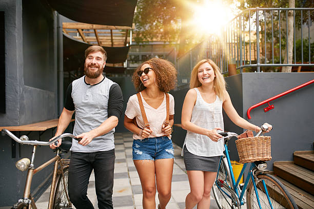 istock Three young adults walking together with bike 498466672