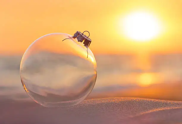 Christmas-tree decoration glass ball at sunset time ocean beach - xmas and New Year's vacation in hot countries concept