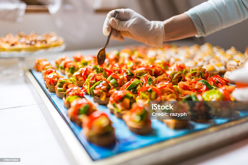 Final touch for tasty canapes Chef is using gloves for adding the final dressing on delicious canapes Food Service Occupation Stock Photo