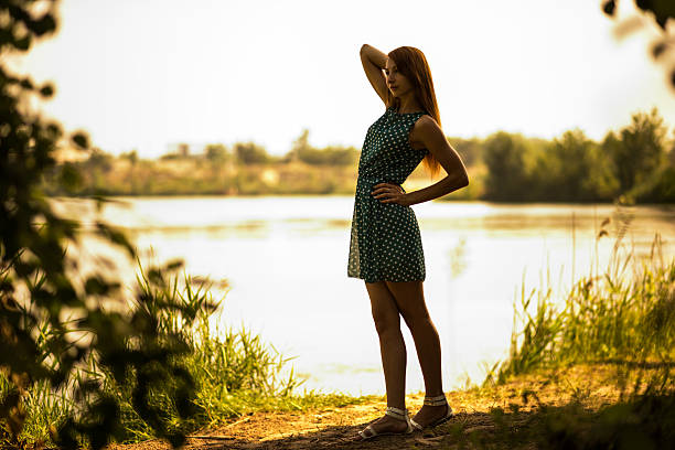 Woman in silhouette in a simple dress at lake