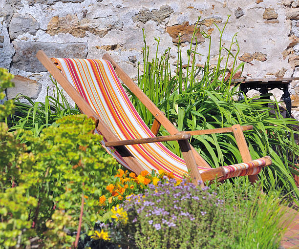 Senior woman in deck chair, relaxing in garden, under an old apple tree