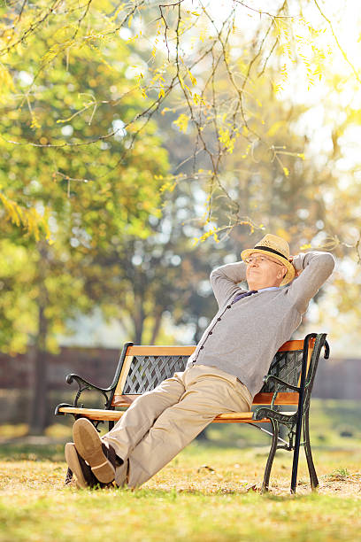 istock Elderly gentleman sitting on a bench in park 498476539