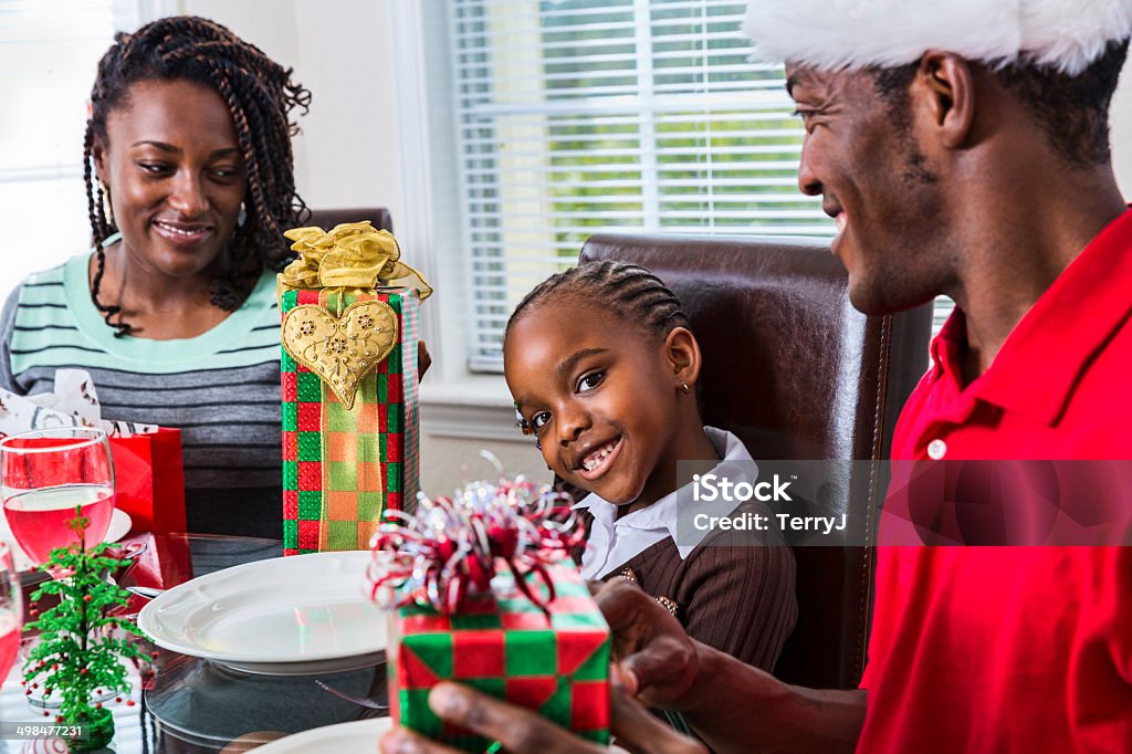 Family Celebrating Christmas before Breakfast A beautiful little girl smiles while her mother and father look on at a Christmas breakfast. African-American Ethnicity Stock Photo