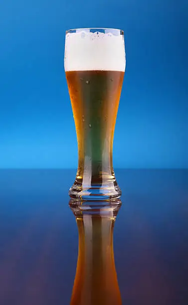 Glass of light beer over a blue background