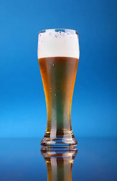 Glass of light beer over a blue background