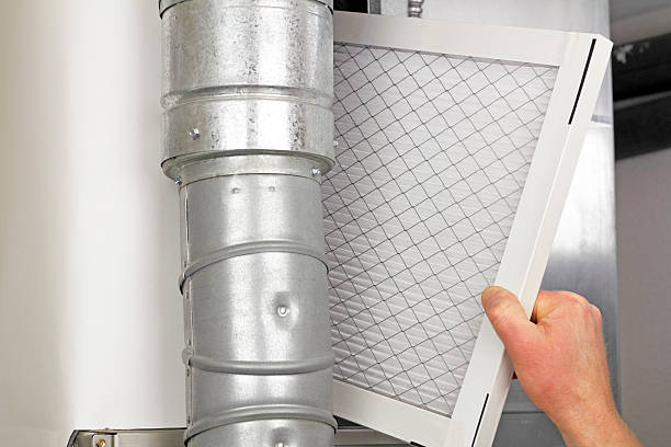 Home Air Filter Replacement Male arm and hand replacing disposable air filter in residential air furnace.. furnace photos stock pictures, royalty-free photos & images