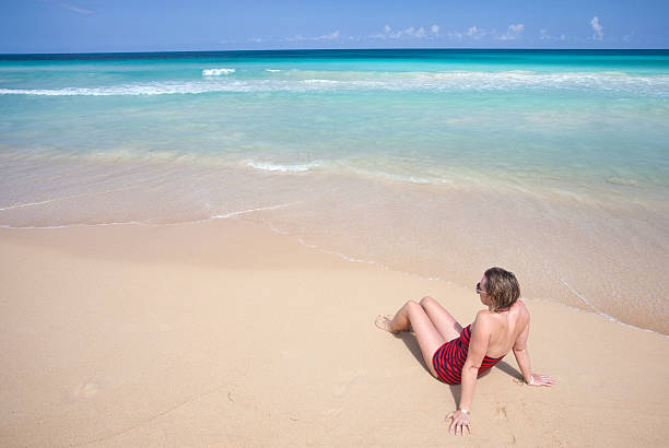 Woman Suntanning on a Tropical Beach A  woman relaxing on a beautiful white sand tropical beach. Dominican Republic. Caribbean. beautiful multi colored tranquil scene enjoyment stock pictures, royalty-free photos & images