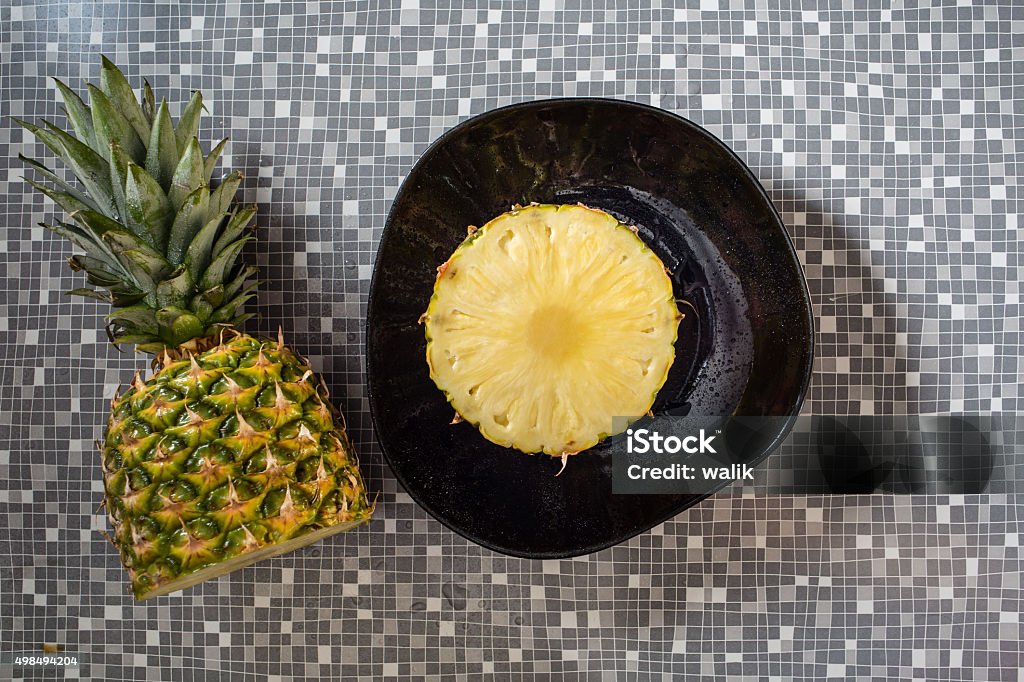 Cross section of pineapple fruit on a black plate. 2015 Stock Photo