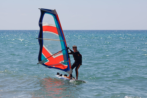 Man on a water sailing windsurfing board. Water sports activity and leasure time