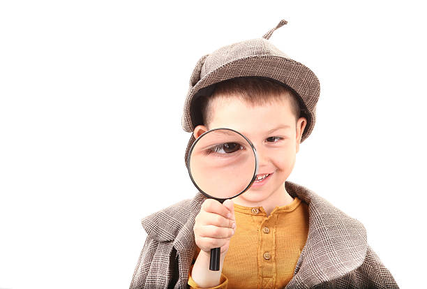 istock Detective boy is looking through magnifying glass 498499606