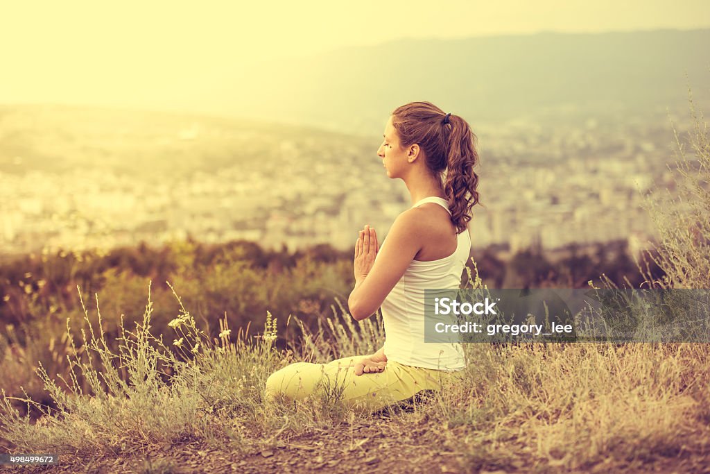 Sport Young woman sits in yoga pose with city on background. Freedom concept. Calmness and relax, woman happiness. Toned image 2015 Stock Photo