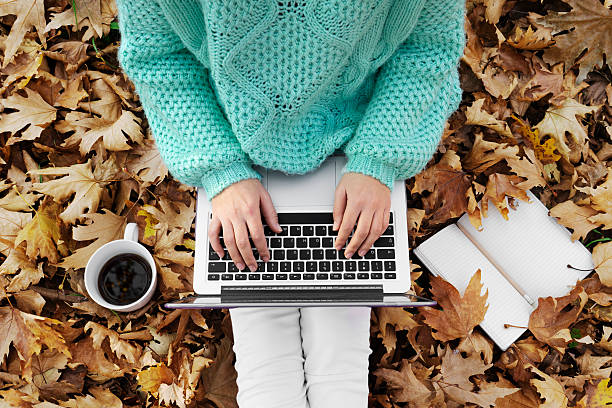 Femme assise en automne feuilles, à l'aide d'un ordinateur portable - Photo