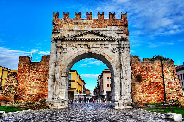 Side view of the Arch of Augustus in Rimini, isolated on shaded blue sky.