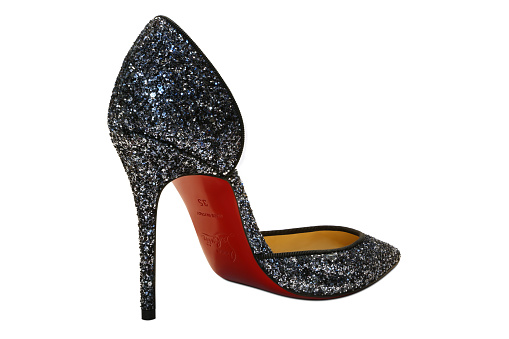 Bloomfield, New Jersey, USA - November 22, 2015: Christian Louboutin red heel shoe with sequins all around the high-end style shoe and was shot on a white background with soft shadow.