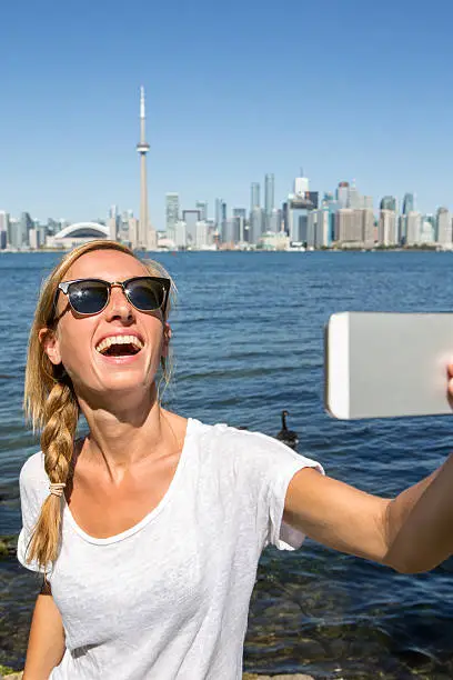 Photo of Cheerful young woman takes selfie in Toronto