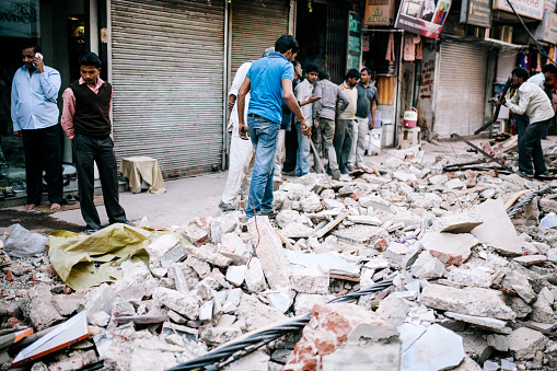 Delhi, India - March 11, 2014: Men salvage and recycle amidst rubble on a street, Delhi, India