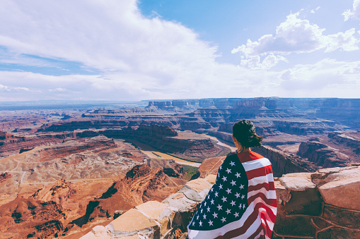 Woman Holding US Flag at Grand Canyon Landscape, USA