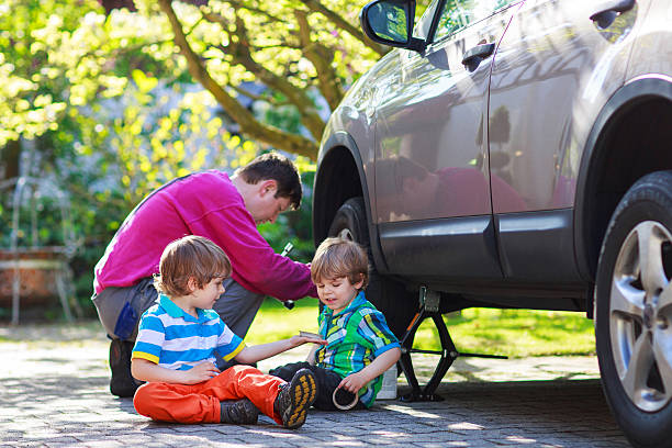 istock father, two little boys repairing car and changing wheel 498511921