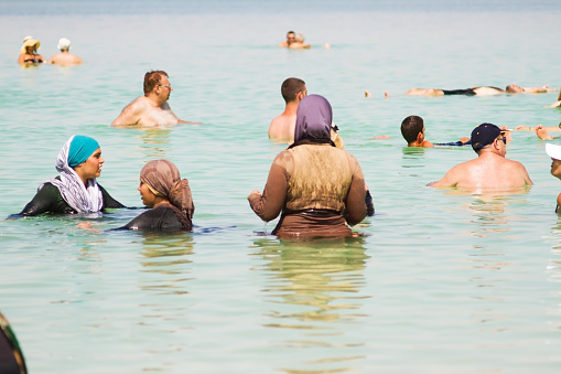 Dead Sea , Israel - June 7 , 2014 : A group of Arab women in traditional Arab clothing bathing in the Dead Sea, among other holidaymakers. Ein Bokek beach. The southern part of the Dead Sea. Israel.