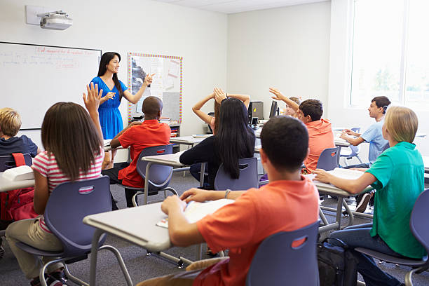 Female High School Teacher Taking Class Female High School Teacher Taking Class Of Teen Students hand raised classroom student high school student stock pictures, royalty-free photos & images