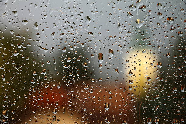 istock Rain drops on window with house and church in background 498523506