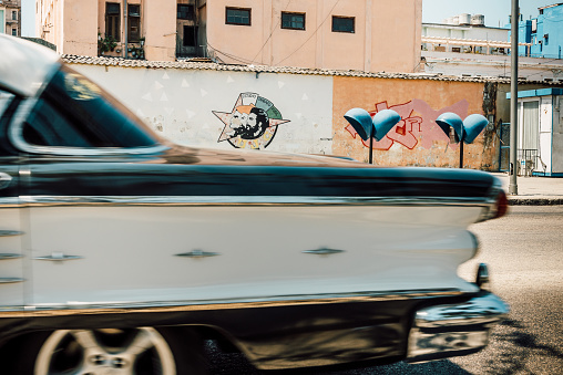 Havana, Cuba - March 19, 2015: A old American car passes a colorful Graffiti with the portrait of Che Guevara, Havana, Cuba