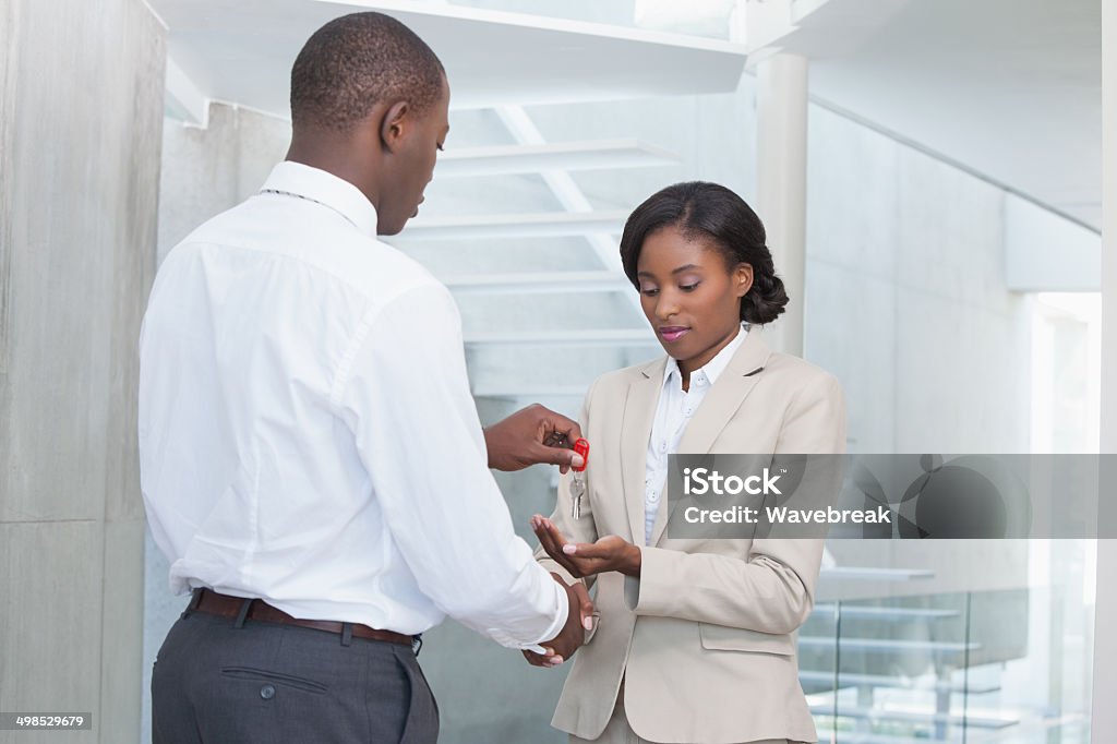 Estate agent giving house key to buyer Estate agent giving house key to buyer in her new home 20-29 Years Stock Photo