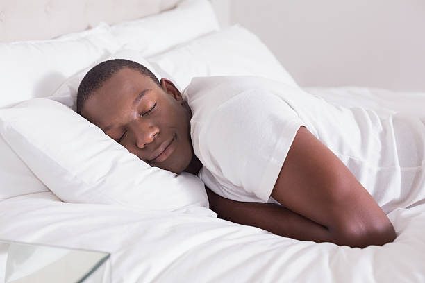 ruhiger mann schlafen im bett - tranquil scene sleeping clothing expressing positivity stock-fotos und bilder