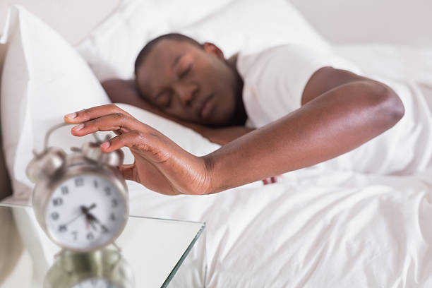 istock Sleepy man hitting his alarm clock in the morning 498529865