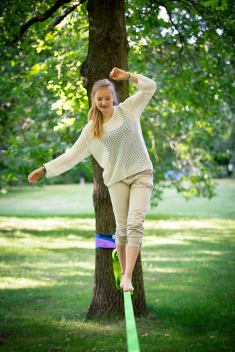 young woman in park balancing on a slackline