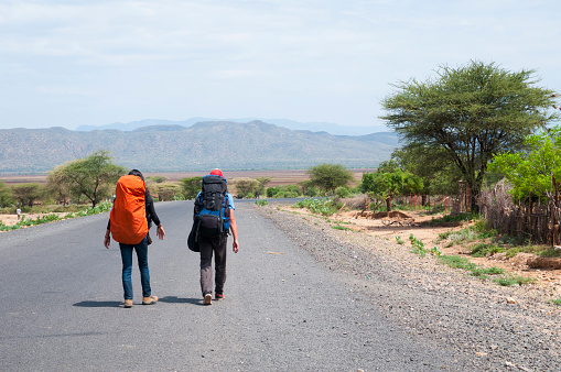 Two backpackers, from Israel and Denmark, walk down a highway in southern Ethiopia near the town of Weyto, Ethiopia, hoping for a ride.