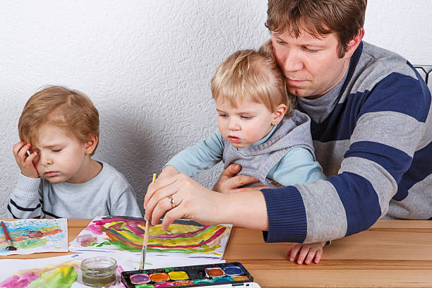 istock Father and two little boys siblings having fun painting 498531527