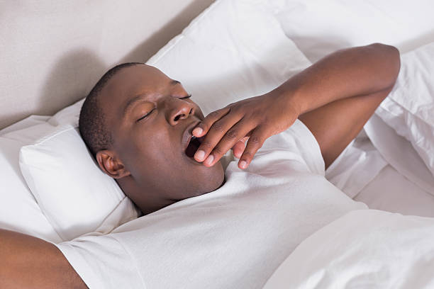 istock Well rested man lying in bed yawning 498532569