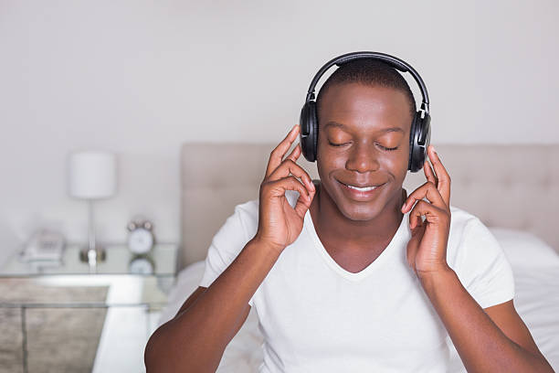 heureux homme, assis à côté de son lit en écoutant de la musique - at the edge of audio photos et images de collection