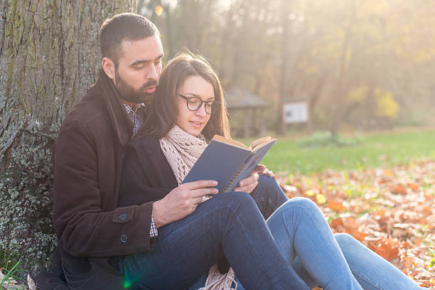 istock Young couple reading book in the park 498536958