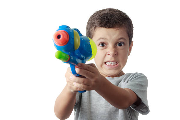 istock Little boy with funny expression playing with plastic water gun 498546788