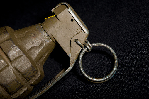 Close up of a World War Two hand grenade, against a black background.