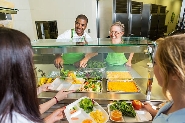 Friendly cafeteria workers serving healthy food to high school students Friendly cafeteria workers serving healthy food to high school students cafeteria worker photos stock pictures, royalty-free photos & images