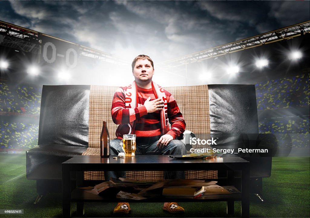 soccer fan on sofa happy soccer or football fan with hand on heart on sofa at stadium Soccer Stock Photo