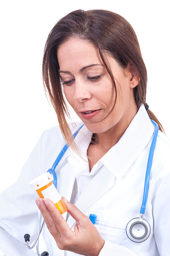Pretty Hispanic female doctor reads prescription medication label on white background