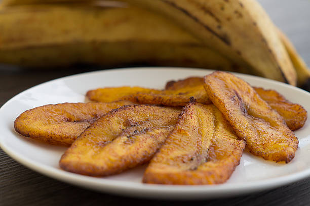 Fried Sweet Plantain / Slices / Ripe Freshly fried sweet plantains served on a white plate.  Green plantains will ripen in a few days.  When the plantain changes color from green to yellow and it becomes softer to the touch with a few speckles, is time to peel, slice and fry the sweet plantain.  It is usually served with meals. plantain stock pictures, royalty-free photos & images