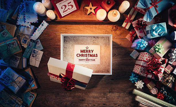 Open gift box with a Merry Christmas and Happy New Year message, presents and Christmas letters all around, desktop top view