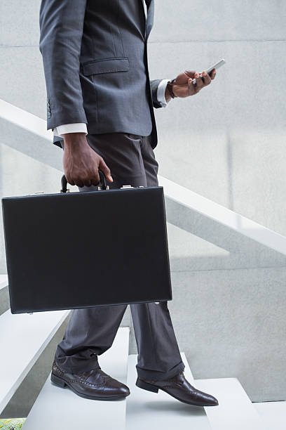 istock Businessman holding briefcase walking down stairs sending a text 498553203